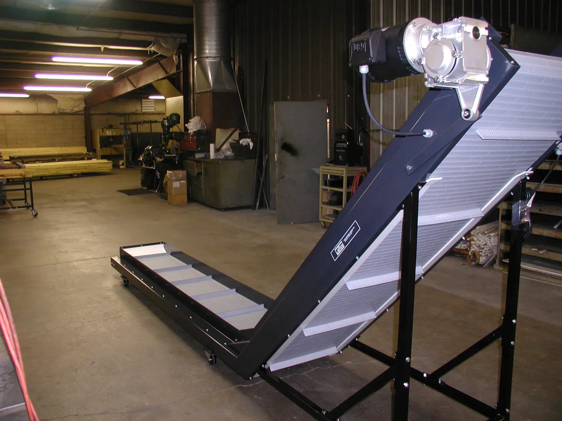 Black LaRos horizontal-to-incline conveyor with cleated belt in the Portage, Michigan shop